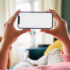 Close Up Of Woman Looking At Blank Screen Of Mobile Phone Lying On Sofa At Home Held Horizontally
