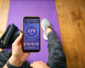 Close Up Of Woman About To Exercise Looking At Heart Rate App On Mobile Phone