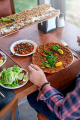 Traditional delicious Turkish foods; Lahmacun (Turkish pizza). Lahmacun traditional Turkish pizza and wraps with salad isolated on rustic wooden table.