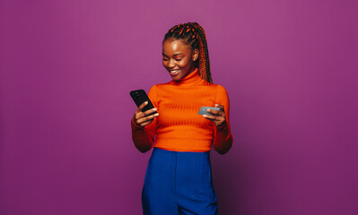 Happy gen z woman smiling and paying online with credit card on vibrant purple background