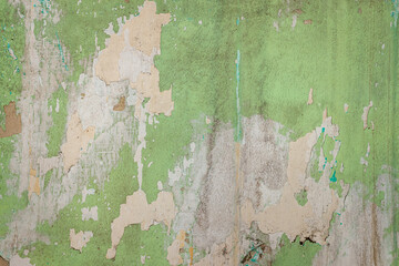 Texture of several times painted green weathered wall with peeling of previous layers of paint.