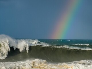 a rainbow is shining in the sky over an ocean wave
