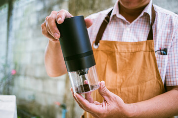 barista presenting a portable coffee grinder in a close-up shot, highlighting essential brewing...