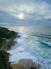 a beach that is close to the water with clouds in the background
