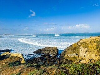 a big rock in the ocean, on a sunny day