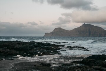 Obraz premium the sea is coming up the shore toward the rock island