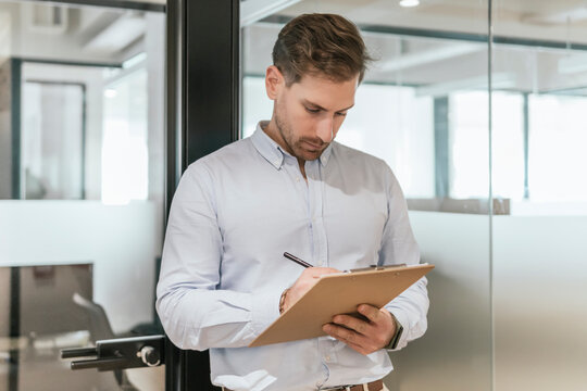 Professional man writing notes in modern coworking space