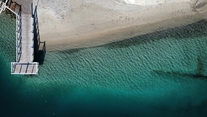 the water is a deep blue and green coloring with a white sand beach in