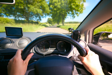 POV Shot Of Woman's Hand On Steering Wheel Driving Along Country Road