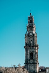 Vertical shot of a weathered church tower in a bright blue sky in Porto, Portugal