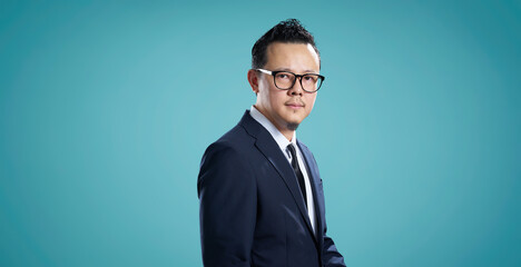 Portrait of a serious businessman with glasses, standing against blue background