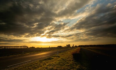 Scenic view of a sunlit asphalt road on a cloudy day