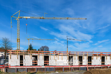Part of a building under construction with the first floor erected and tower cranes against the...