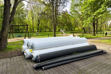 Rolls of artificial grass wrapped in white plastic film folded near the playground.
