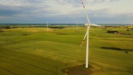 Scenic Aerial view Large Wind Power Turbines with Blades in Field during sunset and rainy sky. Rotating blades generate clean electric power. Concept of electricity saving and alternative power source