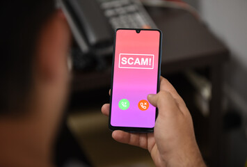 Closeup of male hand holding modern mobile phone with red screen and warning icon with the text 