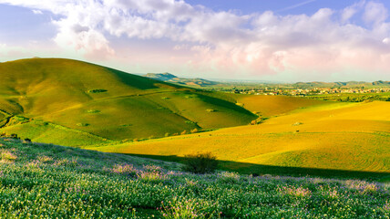 spring or summer beautiful landscape of green hills and flowering meadow with fields and mountains...