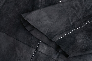 Sleeve detail of a black suede jacket with white contrast stitching