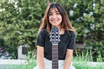 portrait of a young latin woman looking into the camera with an acoustic guitar