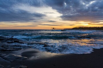 Obraz premium Dramatic seascape at sunset with a pier in the background