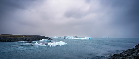 two small pieces of ice floating in the water with rocks below