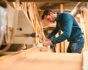 Carpenter Working In Woodwork Workshop Measuring Wood For Project