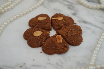 Homemade cookies with almonds and pearls on white marble background.
