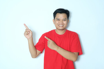 Young Asian man pointing to the right side with excited expression. Wearing a red t-shirt