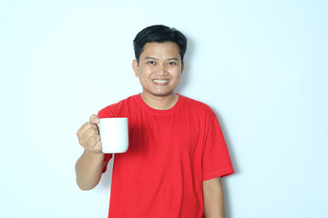 Young Asian man smiling happy while raising the white cup he was holding. Wearing a red t-shirt