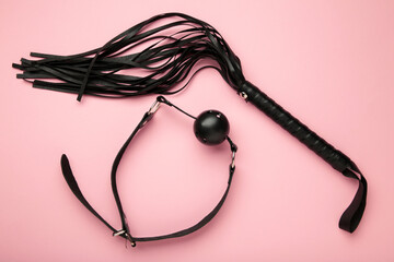 Set of erotic toys for BDSM on pink background. The game of sexual slavery with a whip and gag....