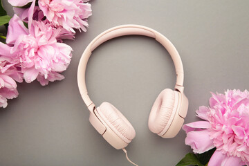 Modern pink headphones with flowers peonies on grey background