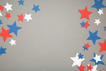 American independence day, celebration, patriotism and holidays concept - red, white and blue paper stars on grey background.