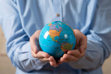 Close-up of man holding a globe in his hands. The concept of the individual's care for the planet's well-being.