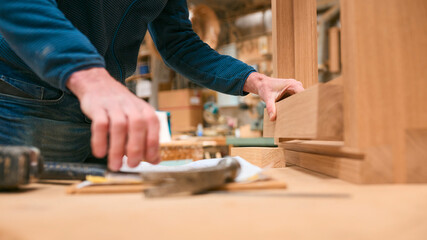 Close Up Of Carpenter In Workshop Gluing Wood To Window Frame