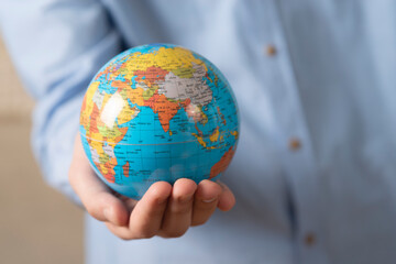 Close-up of man holding a globe in his hands. The concept of the individual's care for the planet's...