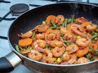 Closeup of a pan with shrimp and vegetables