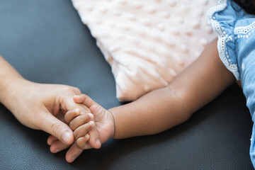 Selective focus on hand of cute African little newborn 7 months old baby girl with black curly hair...