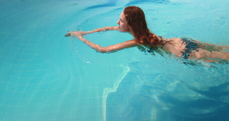 A woman is swimming in a pool without a shirt on. The setting is a pool in a resort on Koh Phangan...
