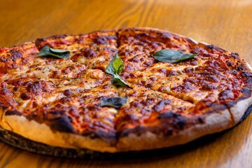 a whole pizza sits on a table with some basil leaves