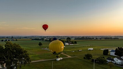 Obraz premium Aerial View of Three Hot Air Balloons Setting Up to Launch, With One in the Air, Floating Away