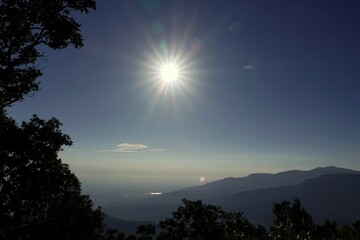 the sun is shining brightly in a blue sky above mountains