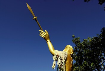a gold statue of a warrior holding an arrow and spear