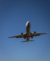 Low-flying airplane with its landing gear deployed against a clear blue sky in Washington DC