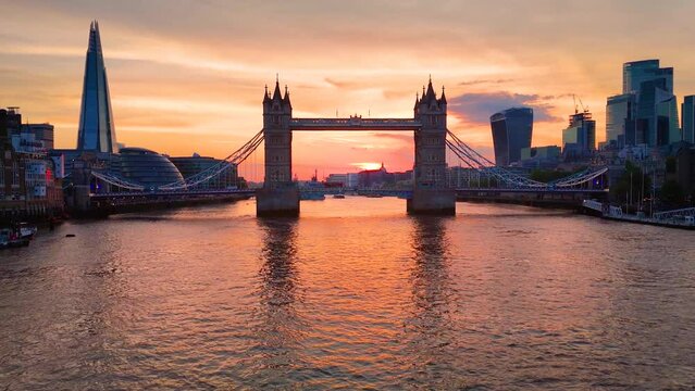 Boat perspective and aerial view towards the skyline and Tower Bridge of London, England, during a beautiful, orange sunset