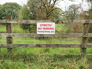 a wooden fence with signs that say strictly no parking in this field