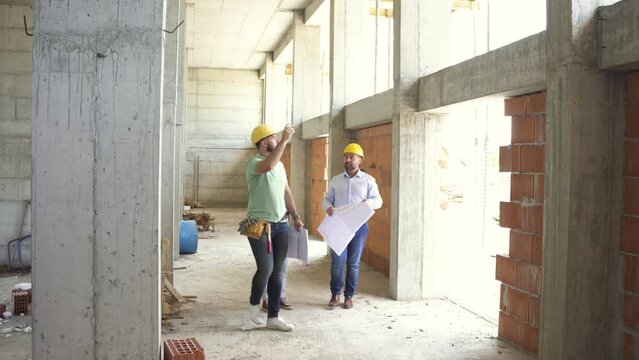 
A building inspector and a construction manager discuss and check the progress of a construction site, ensuring everything meets regulations and plans.