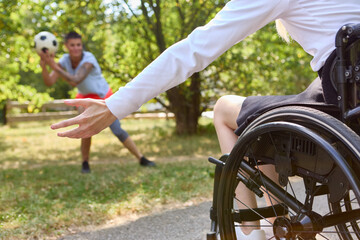 Person in wheelchair playing soccer with friend in sunny park
