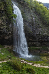 Fontanon of Goriuda, Udine. Wonderful waterfall that falls from a cliff. The force of the waterfall is a sight to behold. Hiking, trekking in the open area surrounded by woods. Summer holidays, peace.