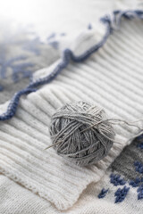 Knitting a winter sweater with patterns. Gray ball with a needle for stitching details.