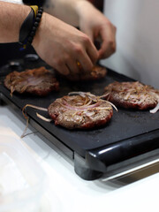 chef friendo a la plancha hamburguesas de carne de ternera con cebolla